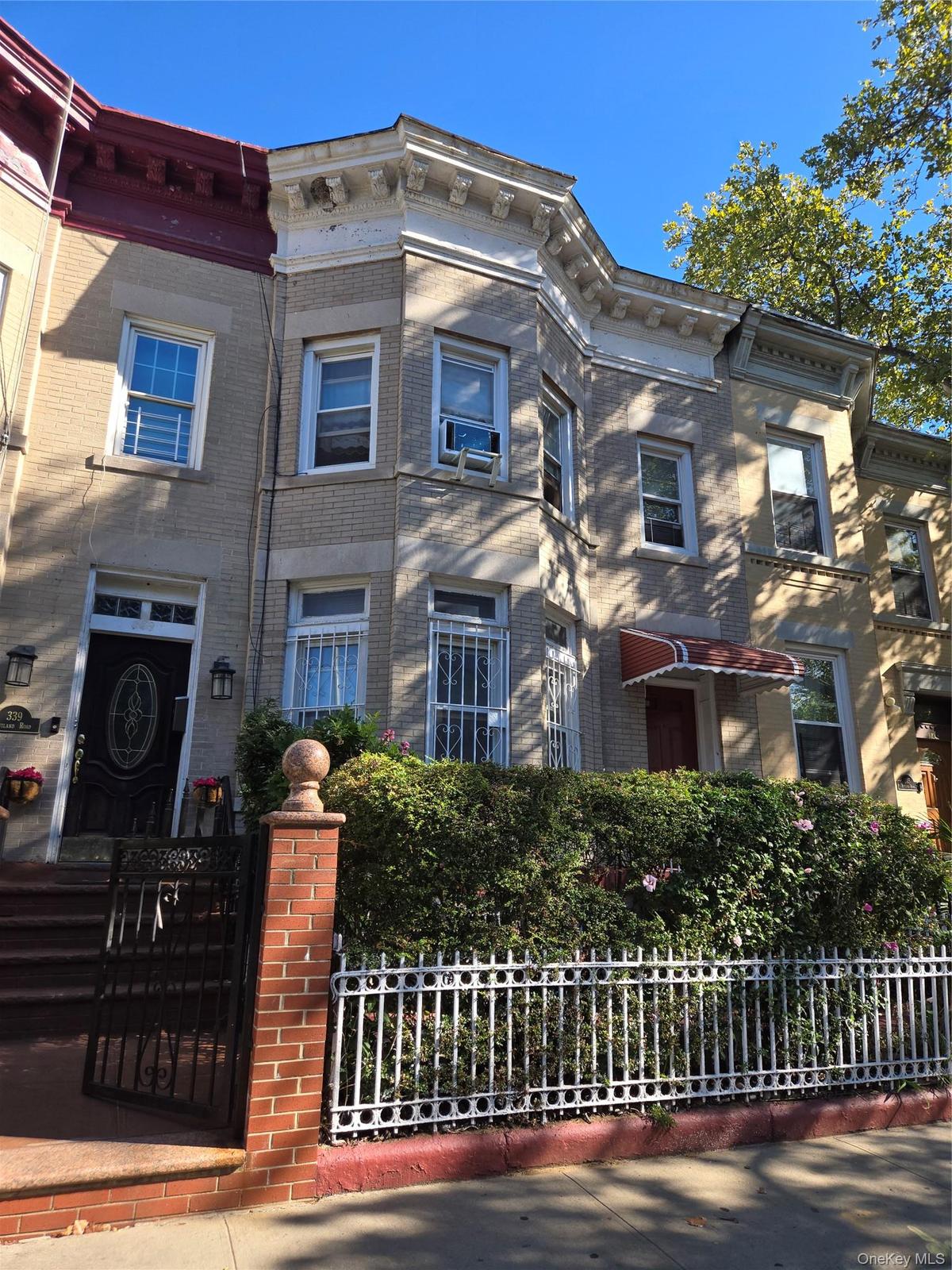 Italianate-style house with brick siding and a fenced front yard