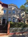 Italianate-style house with brick siding and a fenced front yard