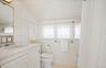 Bathroom featuring a decorative wall, vanity, toilet, and lofted ceiling