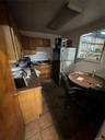Kitchen with fridge, dark countertops, dark tile patterned flooring, and brown cabinets