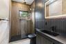 Contemporary bathroom featuring a walk-in shower with a gold-tone rain showerhead, a black toilet, and a vanity with an integrated sink and matte blac