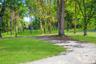 Surrounding community with a lawn and view of wooded area