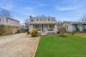 New england style home featuring covered porch, a chimney, and driveway