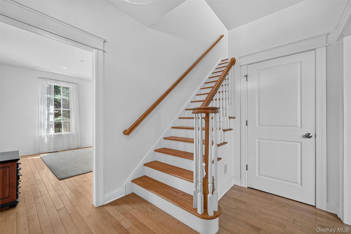 The bright foyer opens to hardwood floors, tall ceilings, and a graceful staircase leading to the second level.