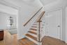 The bright foyer opens to hardwood floors, tall ceilings, and a graceful staircase leading to the second level.
