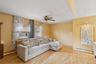 Living room with baseboard heating, light wood finished floors, ceiling fan, and cooling unit