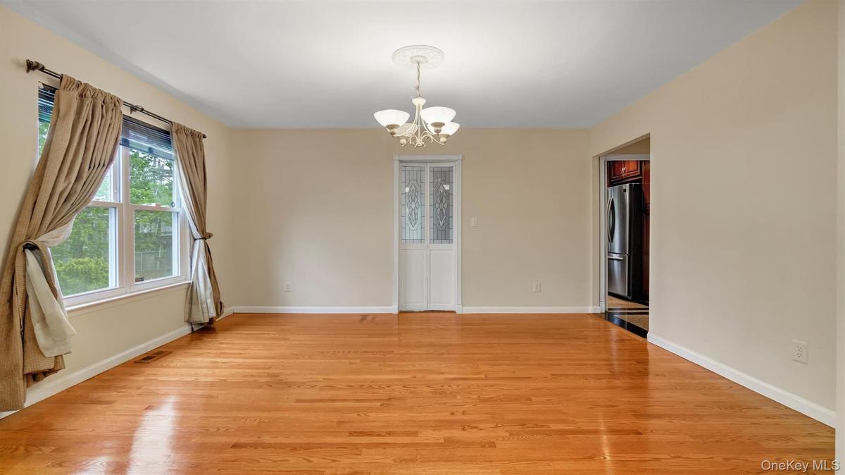 Spare room featuring an inviting chandelier, baseboards, visible vents, and light wood-style floors