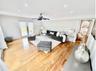 Living area featuring a decorative wall, wood finished floors, wainscoting, recessed lighting, and a ceiling fan