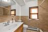 Full bath with vanity, a baseboard heating unit, tiled shower, tile walls, and light tile patterned flooring