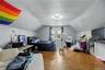 Sloped ceiling room featuring wood-finish flooring, a double window, and a flush-mount light fixture