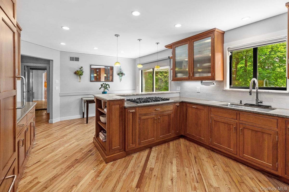 Kitchen with a sink, stainless steel gas stovetop, visible vents, a peninsula, and brown cabinetry