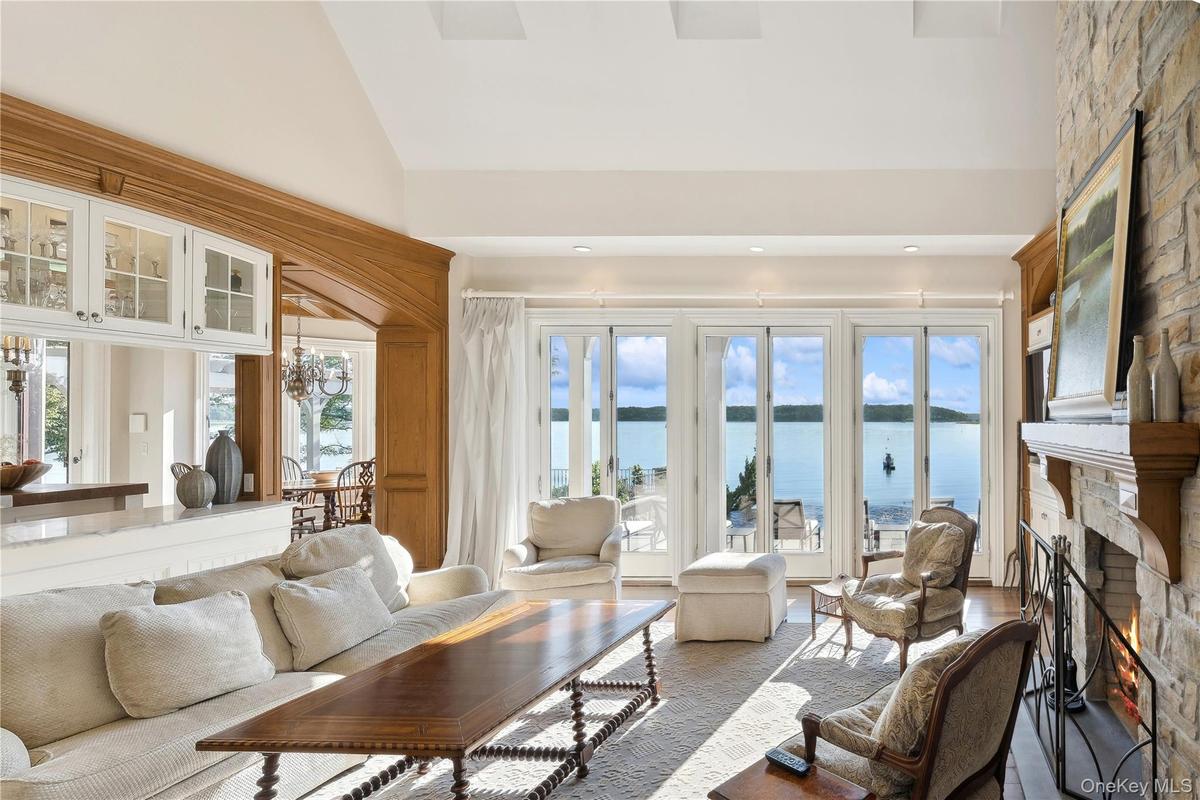 Living room with a water view, a large fireplace, high vaulted ceiling, and recessed lighting