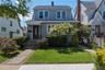 Traditional two-story residence with gray siding and a dark shingled roof. Large Bay window .