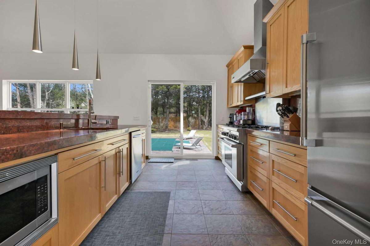 Kitchen with stainless steel appliances, plenty of natural light, a sink, and wall chimney range hood