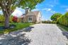 View of front of property featuring a front lawn, driveway, roof with shingles, and a chimney