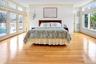 First Floor Primary Bedroom with French Doors to Pool & amazing Bay views. There are wood finished floors, and crown molding.