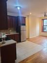 Kitchen with light countertops, cooktop, freestanding refrigerator, tasteful backsplash, and ceiling fan