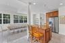 Kitchen with wood cabinetry, stainless steel refrigerator, and a granite-topped island