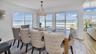 Dining space with baseboards, light wood-type flooring, an inviting chandelier, and a water view