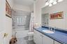 Full bathroom featuring vanity, shower / bath combo, and dark tile patterned flooring