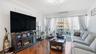 Living area with dark wood-style floors, ornamental molding, a warm lit fireplace, and a wall unit AC