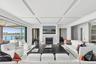 Living area featuring coffered ceiling, wood finished floors, a water view, a tiled fireplace, and beam ceiling