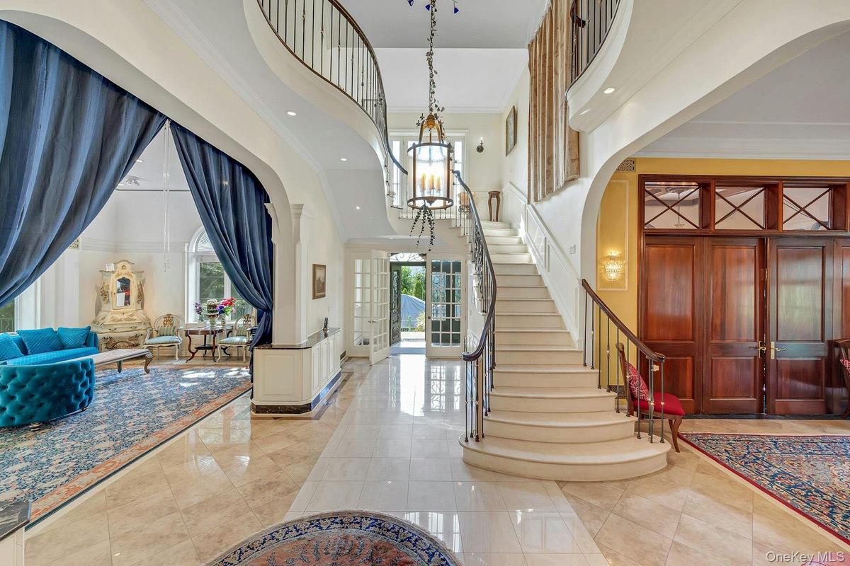 Entrance foyer with a high ceiling, stairway, ornamental molding, recessed lighting, and arched walkways