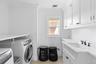Laundry room featuring washing machine and clothes dryer, cabinet space, and ornamental molding
