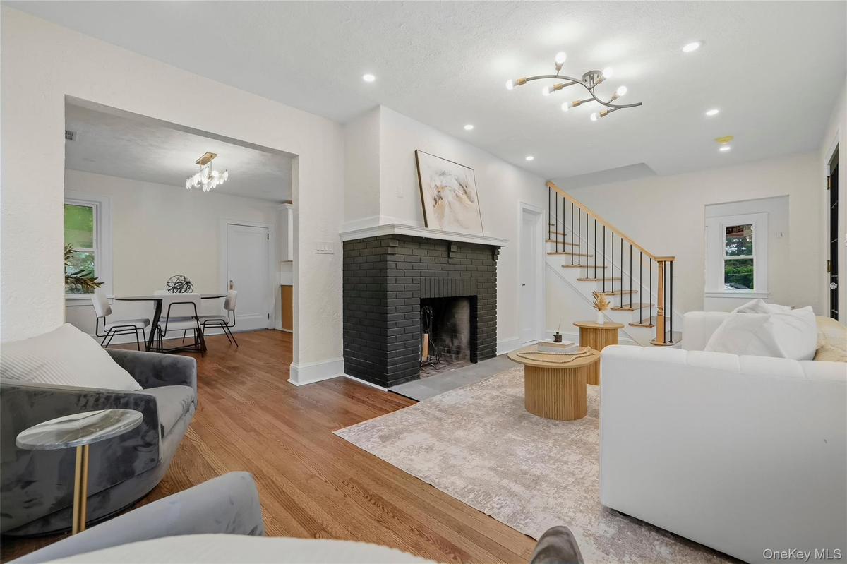 Living room featuring wood-finish flooring, a black brick fireplace, recessed lighting, and a modern ceiling light fixture