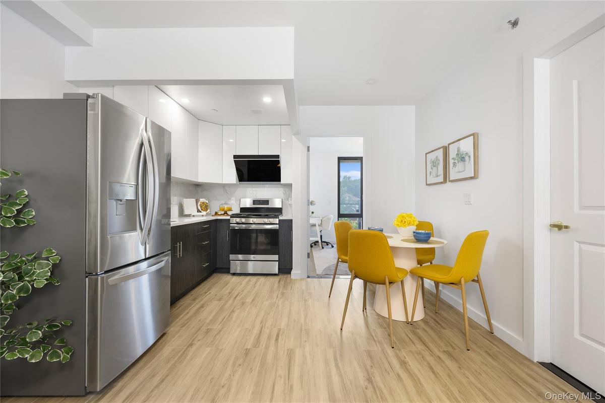 Kitchen with modern cabinets, light wood-style floors, white cabinetry, light countertops, and appliances with stainless steel finishes