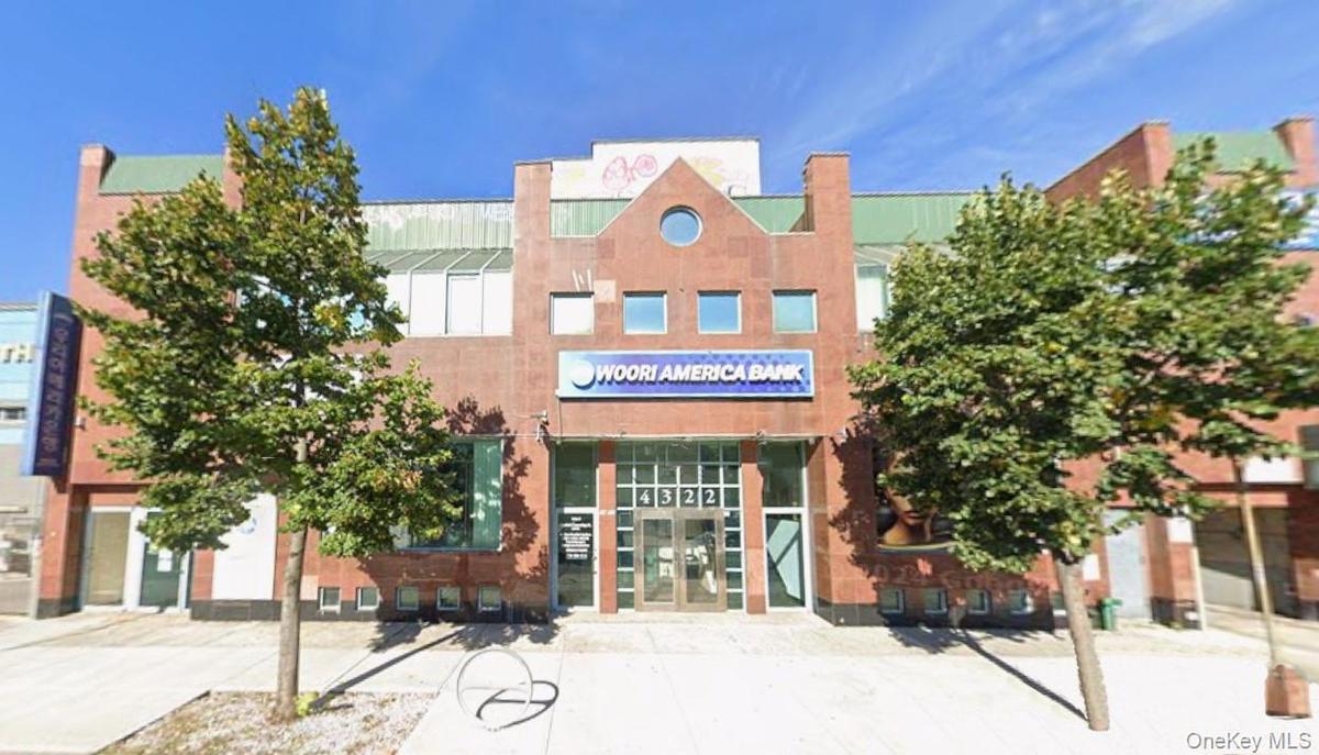 Brick facade commercial building featuring an arched entrance, ground-level storefront windows, and upper-story glazing