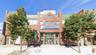 Brick facade commercial building featuring an arched entrance, ground-level storefront windows, and upper-story glazing