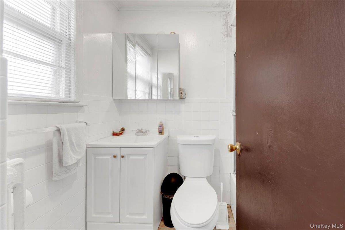 Half bath with vanity, tile walls, and radiator