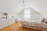 Bedroom featuring wood finished floors, vaulted ceiling, and wainscoting