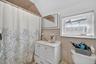 Bathroom with vanity, tile walls, curtained shower, vaulted ceiling, and decorative backsplash
