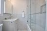 Bathroom with tile walls, combined bath / bathtub with glass door, and vanity