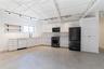 Kitchen with black appliances, concrete floors, open shelves, and white cabinets
