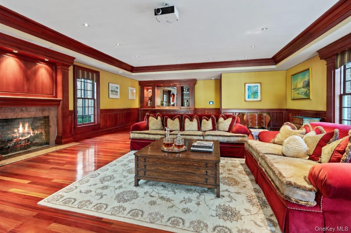 Spacious interior featuring rich wood-finish flooring, a stone-surround fireplace with a wood mantle, and extensive wood paneling and trim