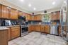 Kitchen featuring wood cabinetry, stainless steel appliances, granite-style countertops, and a tile floor