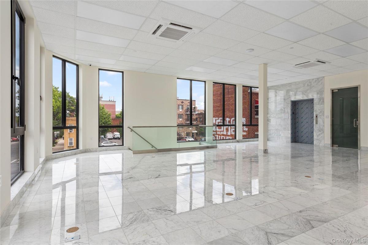 Spare room featuring floor to ceiling windows, a paneled ceiling, and marble tiled flooring