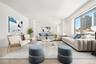 Spacious living area featuring expansive windows, wood-finish flooring, and white walls