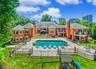 Sprawling brick exterior property featuring multiple balconies, a large inground swimming pool, extensive patio space, and a fenced backyard