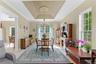 Tray ceiling with decorative medallion, chandelier lighting, and large windows