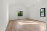 Spacious room featuring vaulted ceilings, recessed lighting, wood-finish flooring, and black-framed windows