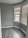 Empty room with wood finished floors, a baseboard radiator, and baseboards