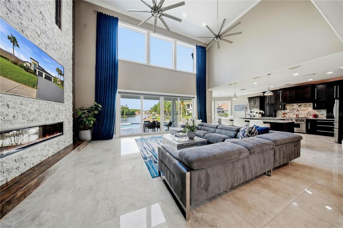 Family room with floor to ceiling stone fireplace with porcelain tile floors