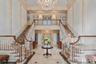 Grand foyer featuring a dual curved staircase with patterned carpet runners, hardwood handrails, and white balusters