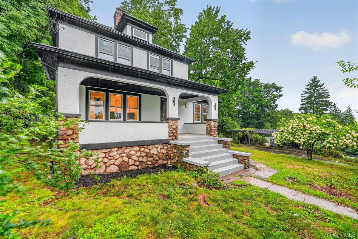 Stucco exterior featuring stone foundation detailing and a covered front porch