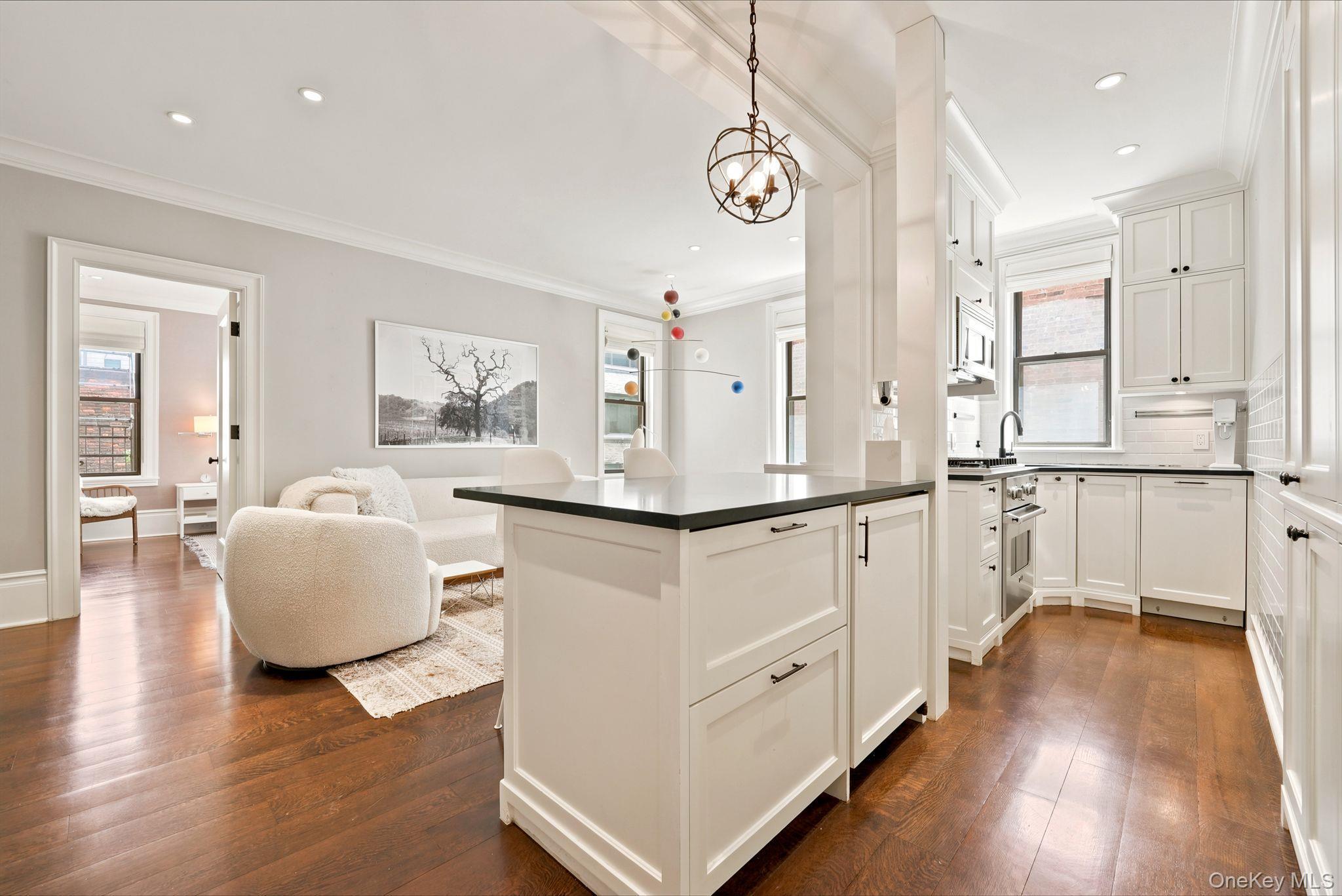Gourmet kitchen with white shaker cabinetry, stainless steel appliances, dark countertops, and wood-finish flooring