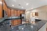 Kitchen featuring rich wood cabinetry, stainless steel appliances, dark granite-finish countertops, and a tile backsplash